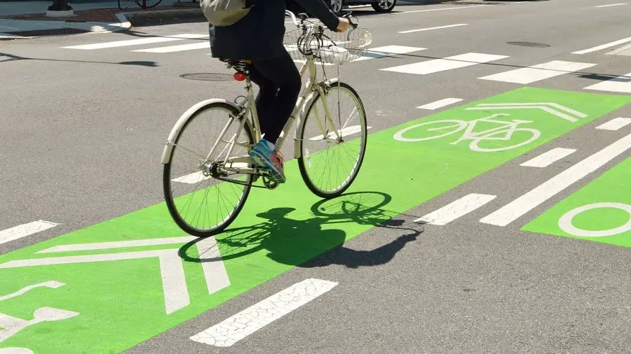 A person is riding a bicycle on a green bike lane markings.