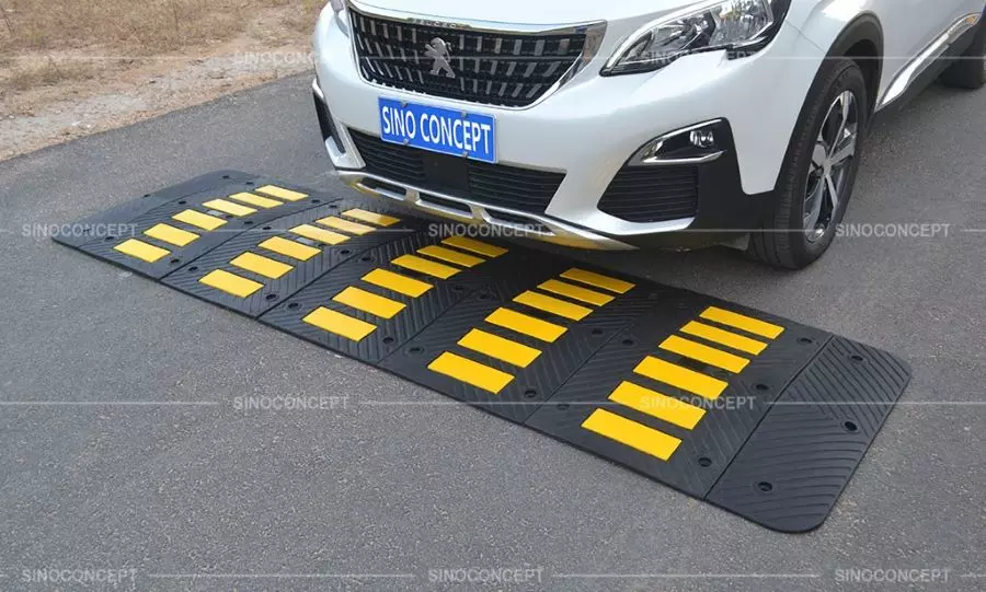 Rubber speed hump made of black vulcanized rubber with yellow reflective tapes as traffic-calming measure.
