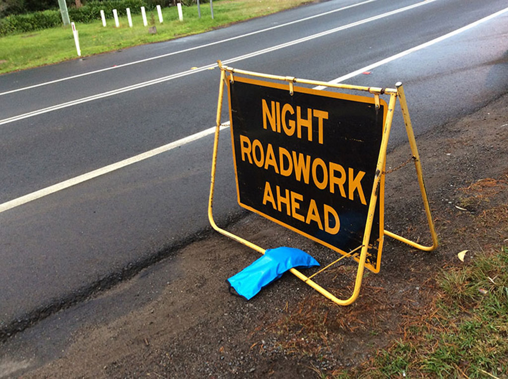 A blue sand bag used to hold down a traffic warning sign