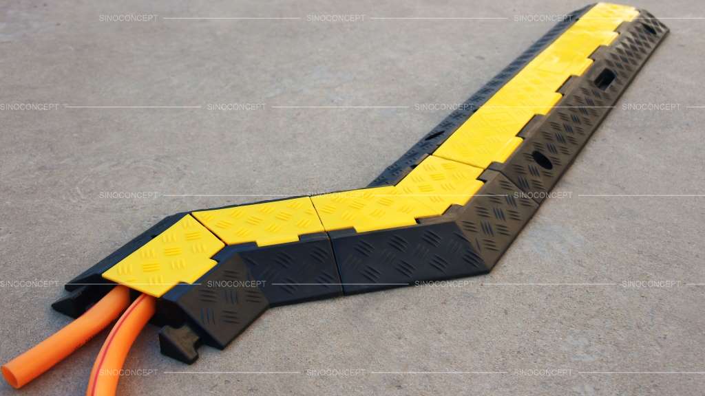 A black rubber cable ramp with yellow covers to protect wires from damage.