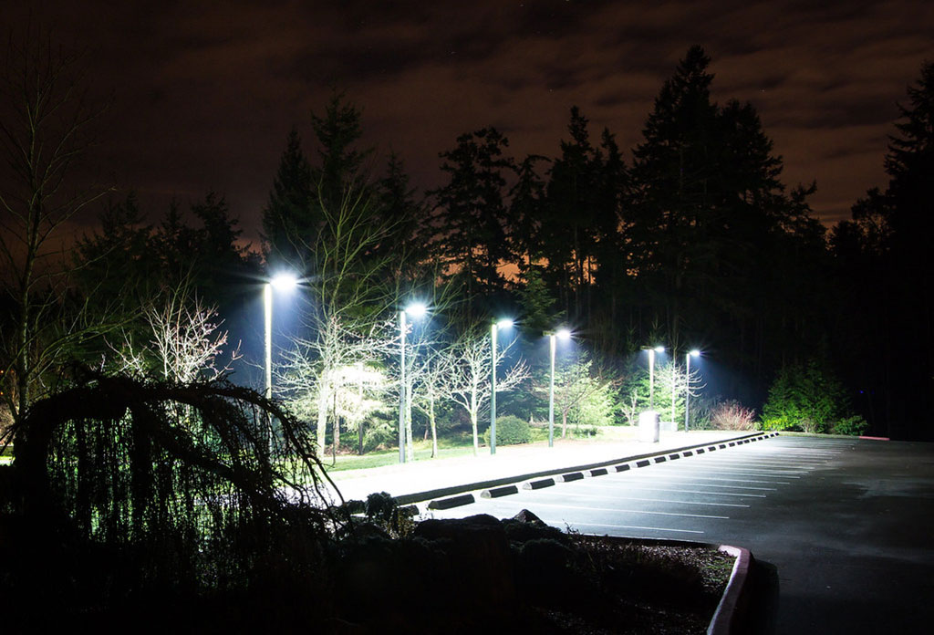 Many car stops are installed in an outside parking lot with lights at night