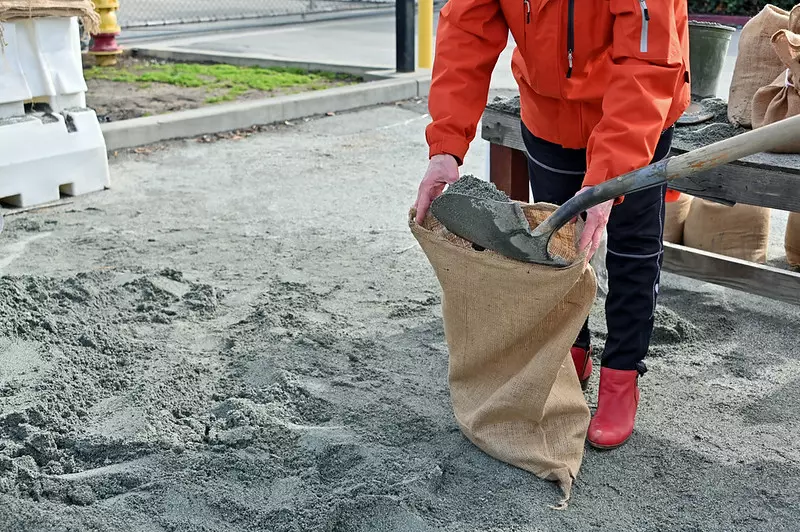 A hessian sandbag is being filled with sand.