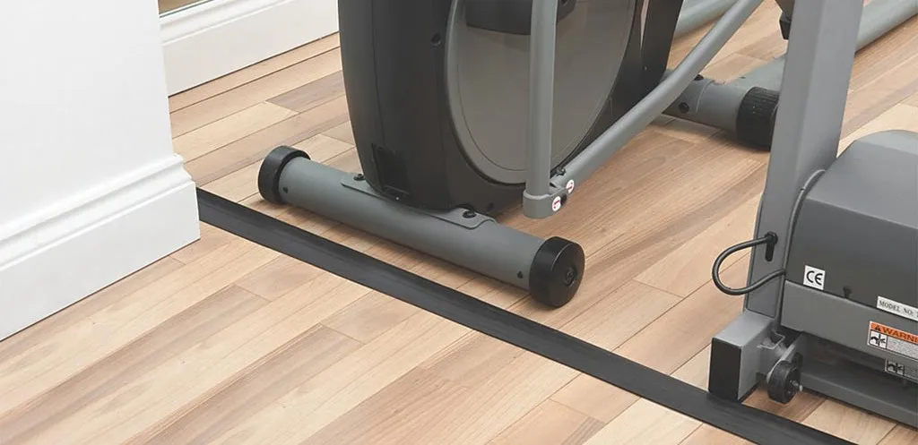 A black floor cord cover used indoors to protect cables.