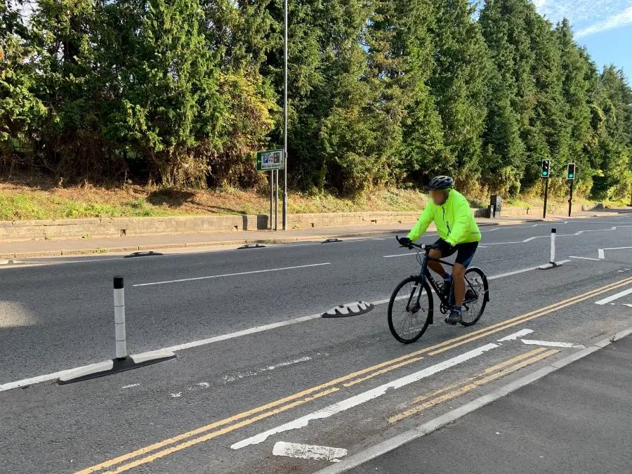 A man in yellow is riding a bike beside the black and white orca lane separators.