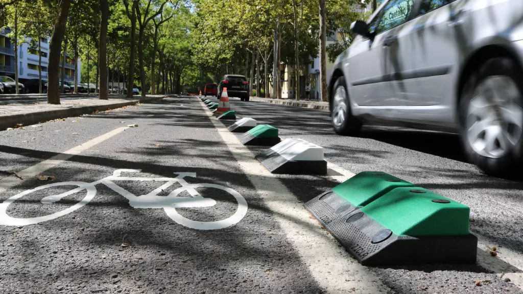 Green and white plastic lane dividers with black base on the road to separate different lanes.