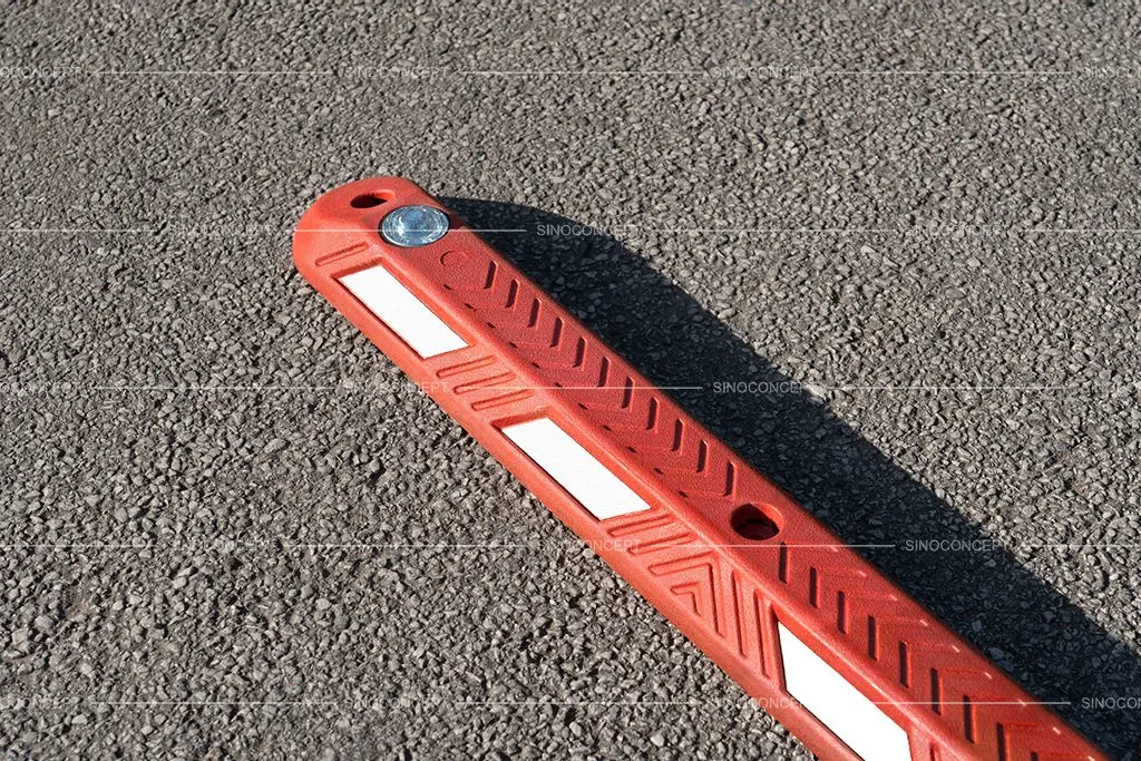A red lane separator made of vulcanised rubber with white reflective stripes and omnidirectional tempered glass studs.