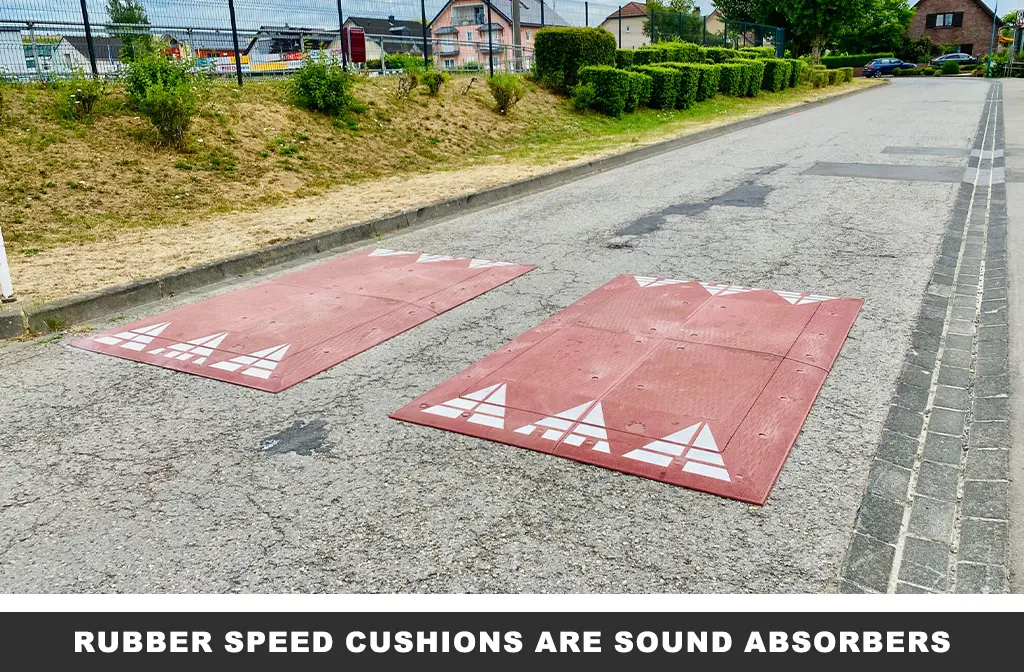 Two red rubber speed cushions with white reflective tapes on the road as traffic-calming measures.