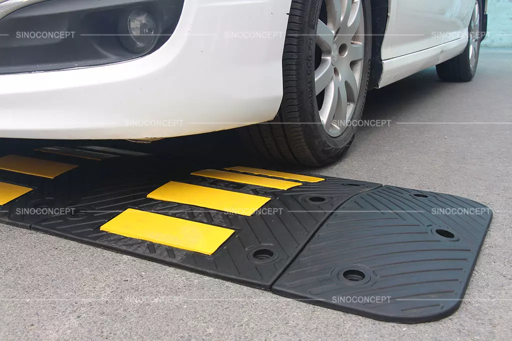 A rubber speed hump made of black recycled rubber with yellow reflective tapes for reducing speed.