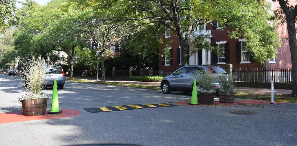 A black and yellow speed hump is mounted on the road as an effective traffic control device.