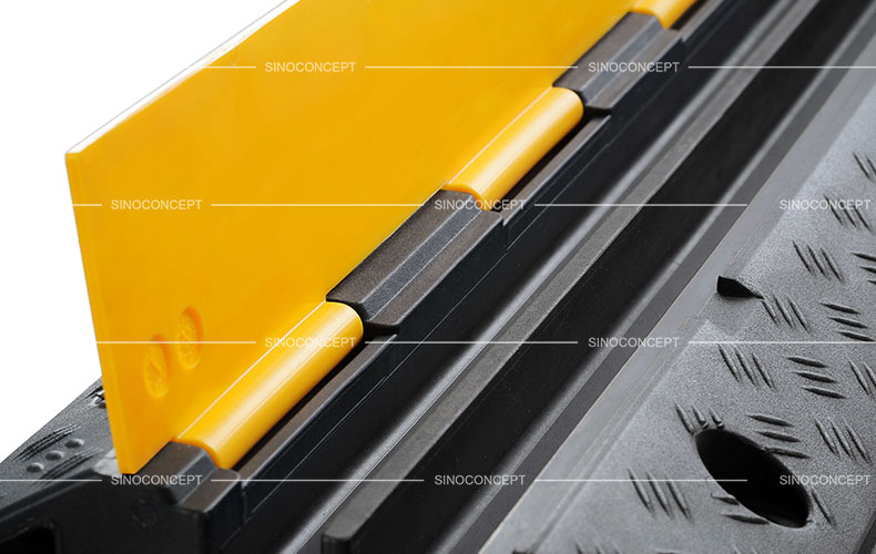 A detailed picture of a two-channel rubber cable ramp with yellow plastic lids.