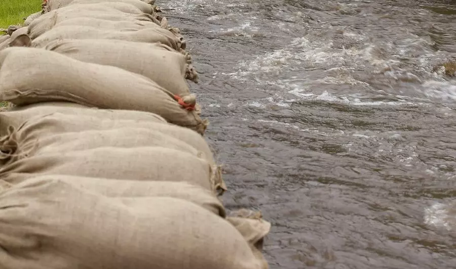 Tied sandbag barriers alongside the river to prevent flooding.