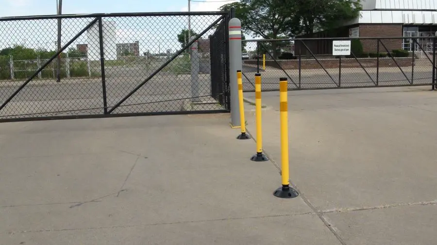 Three yellow delineator posts with black bases mounted on the ground.