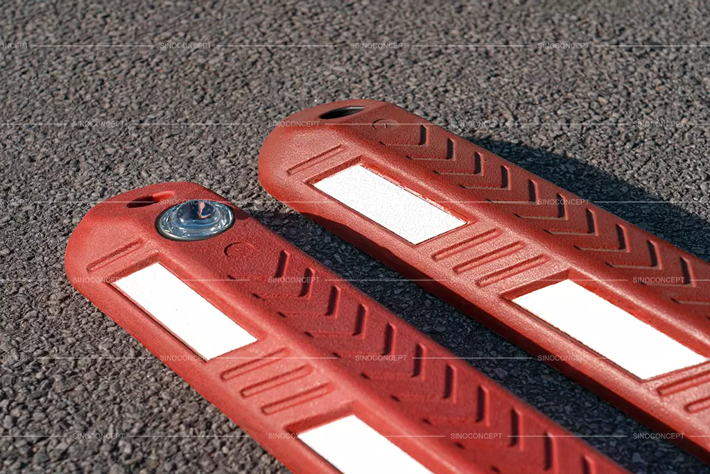 Two lane separators made of red recycled rubber, one of which is embedded with glass bead reflective tapes.