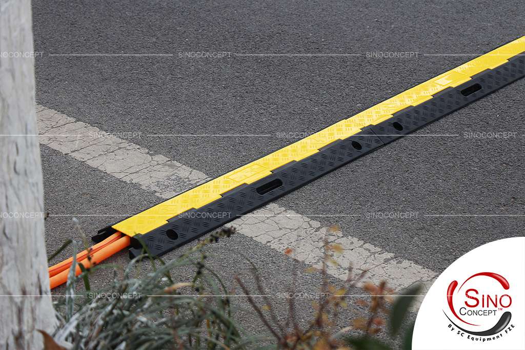 Black rubber cable ramp with yellow strong PVC lids on the ground to protect cables.