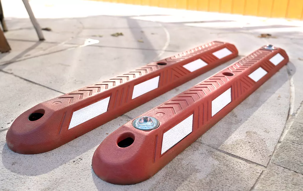 Two red rubber lane dividers with white reflective films and one with road studs embedded