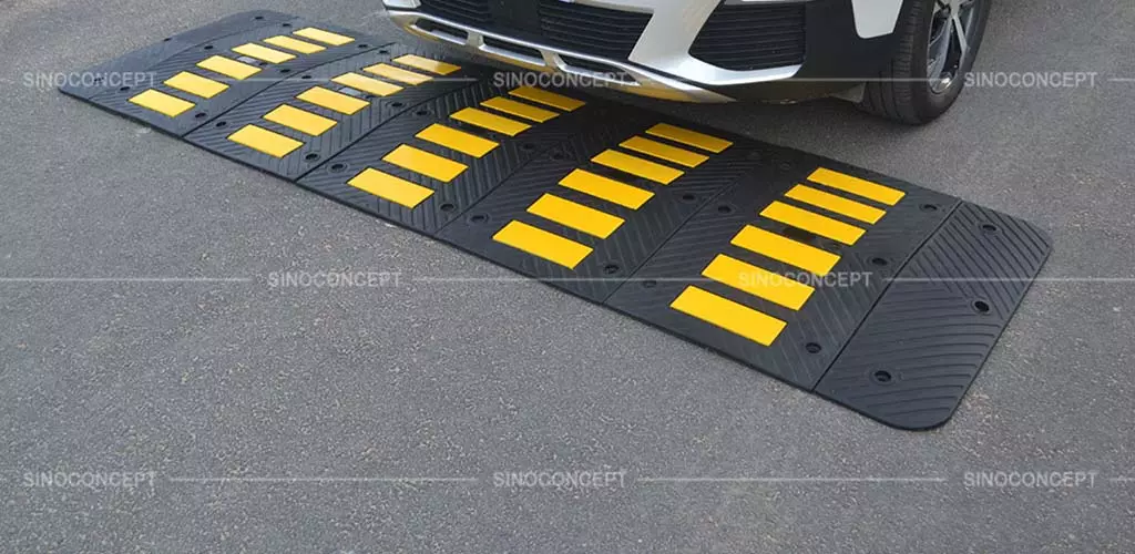 A rubber road hump made of black recycled rubber with yellow reflective tapes for parking management.