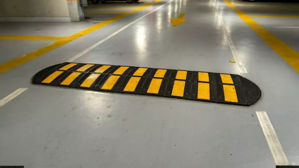 A black and yellow speed hump in a parking lot to reduce vehicular speed.