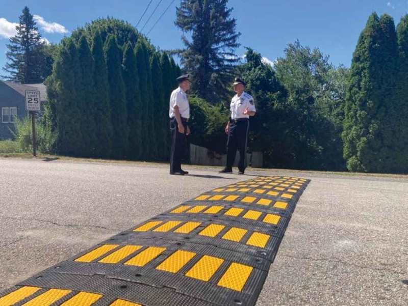 A black and yellow road hump is mounted on the road for traffic safety management.