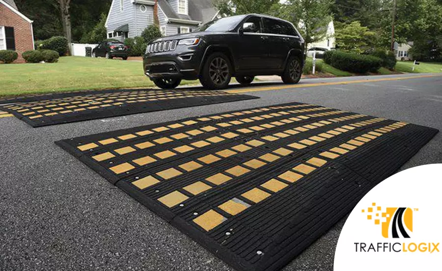 A black car is about to drive over the black and yellow rubber road speed cushions which Traffic Logix manufactures.