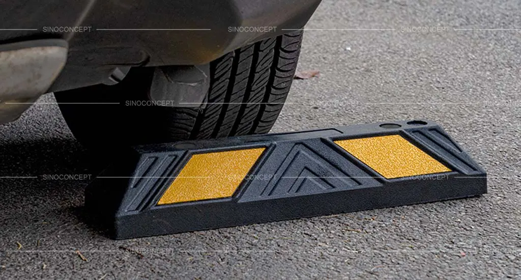 A black rubber wheel stop with yellow reflective films for parking management.