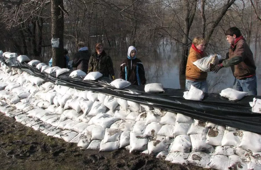 Plenty of white sandbags are put together as a sandbag barricade to prevent flooding.