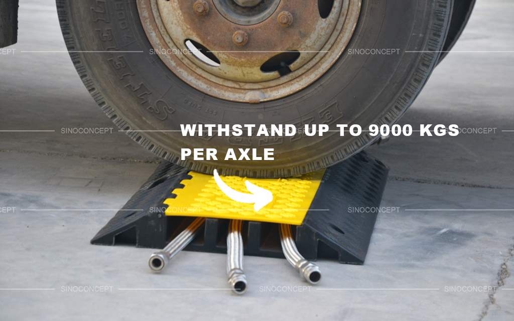 A black heavy-duty cable guard with yellow lids to protect wires from being damaged by heavy wheels.