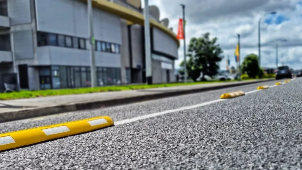 Yellow cycle lane separators made of rubber with white reflective films mounted on the road.