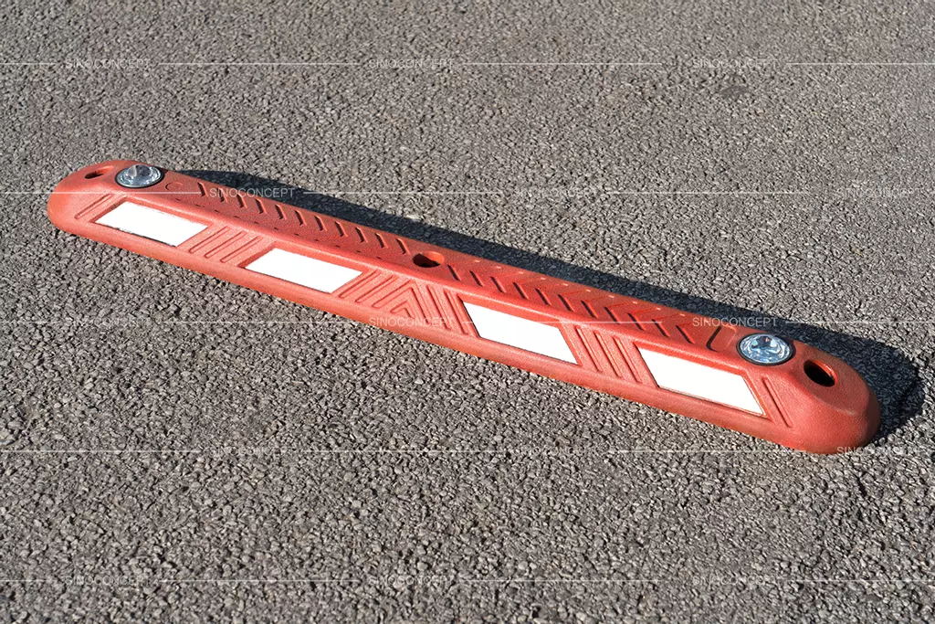 A red rubber lane separator, with white reflective films and road studs to increase visibility at night.