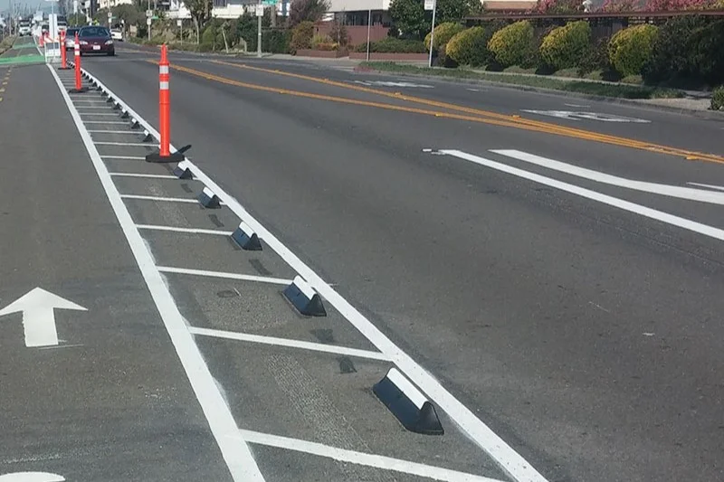 Black rubber cycle lane dividers on the road to separate different lanes.