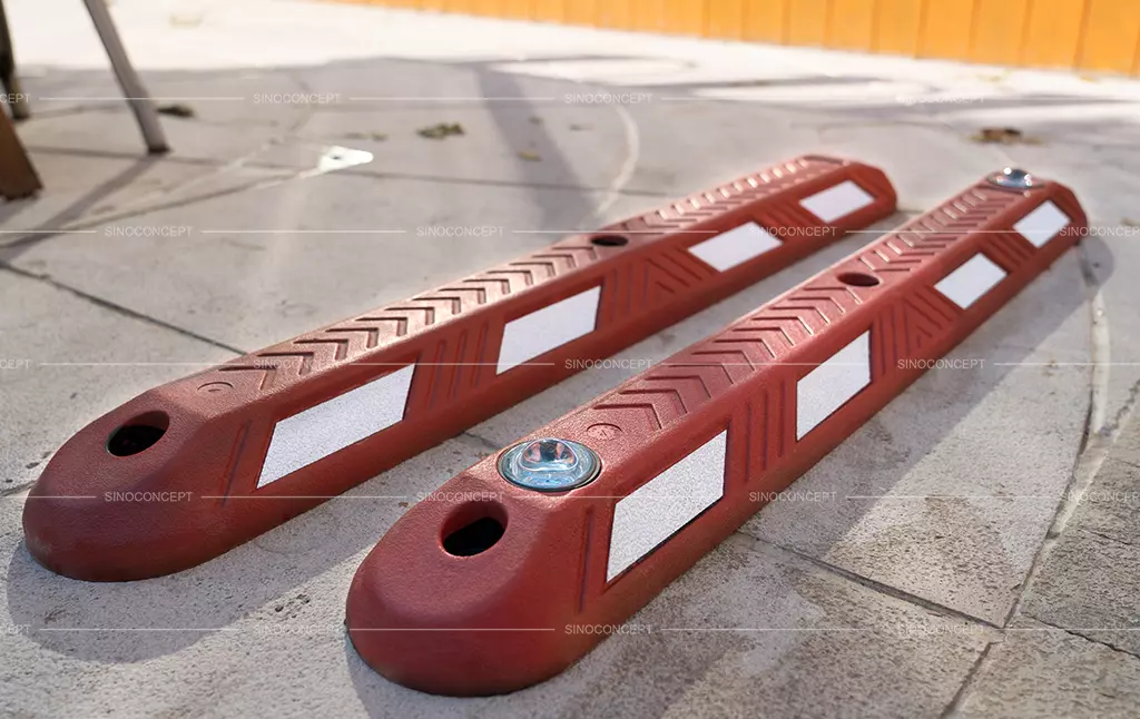 Two red rubber lane separators, affixed with white reflective films, one of which is embedded with road studs.