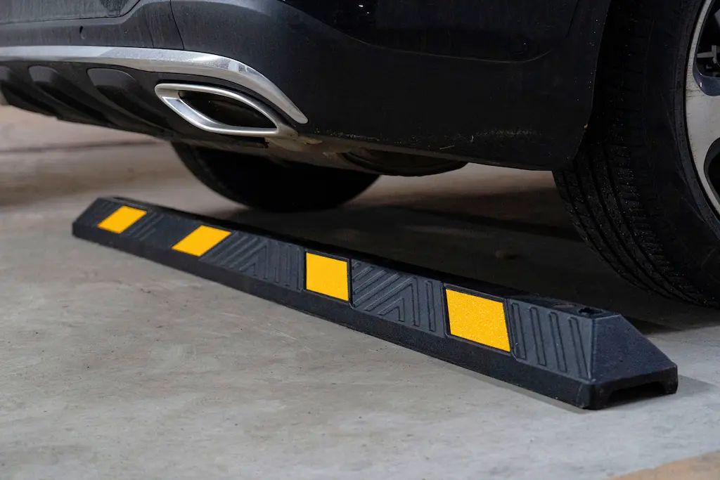 A black rubber parking block with yellow reflective films for car park management.