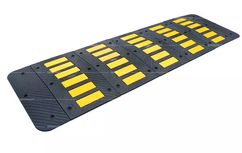 A rubber speed hump made of black recycled rubber with yellow reflective tapes for traffic management.