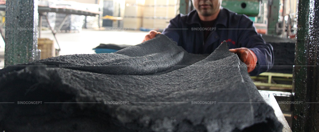 A worker is putting rubber material into a mould machine to manufacture rubber speed humps in Sino Concept factory