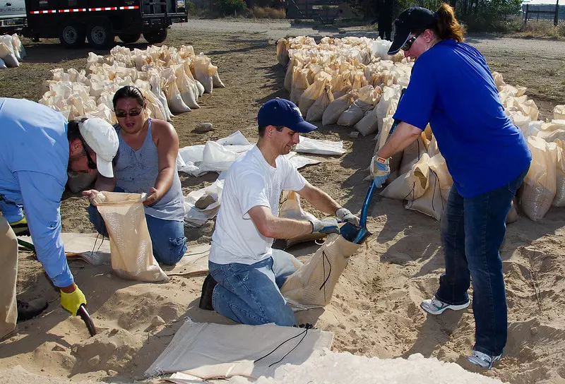 Some people are filling sandbags with the help of spades.