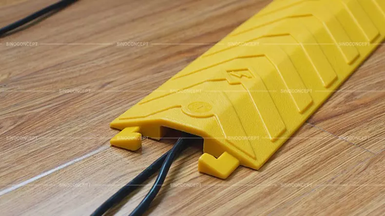A bright yellow drop-over cable protector made of polyurethane to protect two black wires.