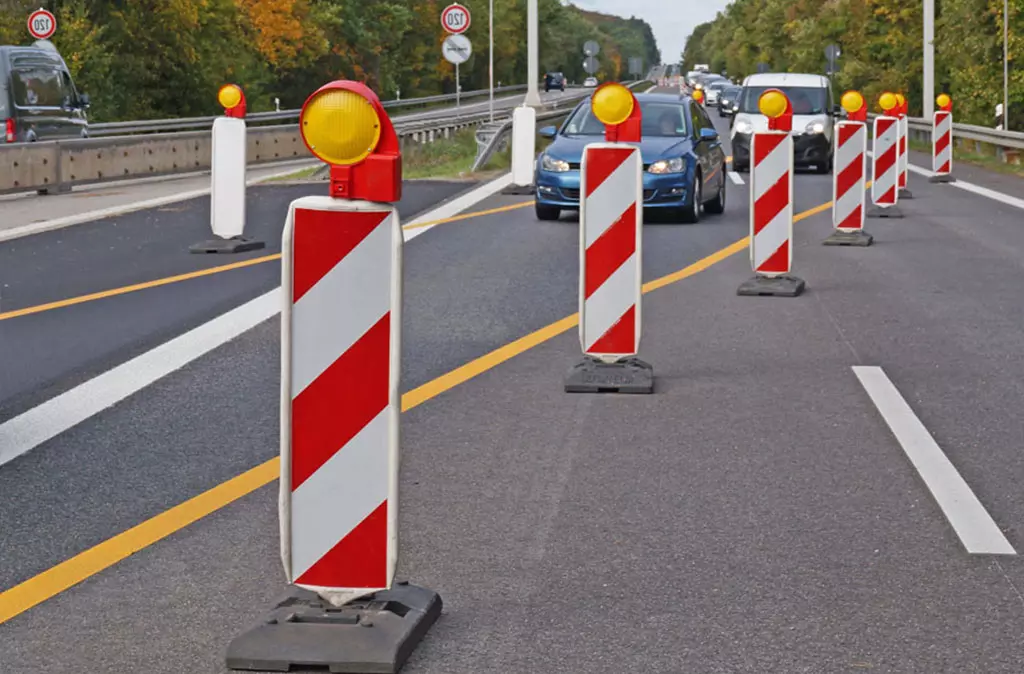 Red and white plastic road beacons with lamps on the top on the road for traffic-safety management.