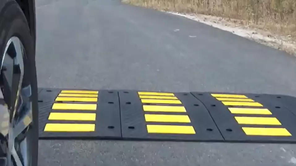 Speed hump made of black rubber and yellow glass bead reflective tapes for traffic management.