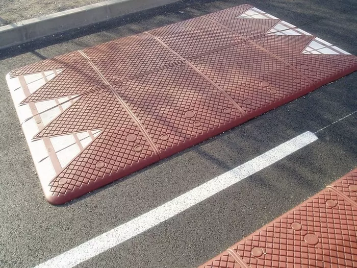 Europe style red rubber speed cushions are mounted on the road as speed traffic-management tools.
