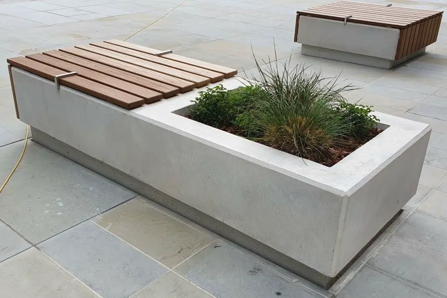 Some plants are planted in a concrete planter.