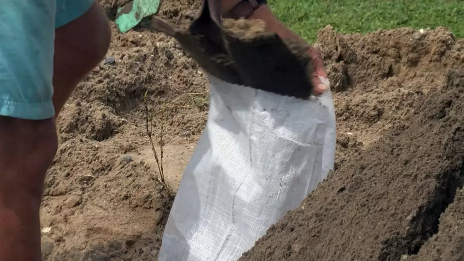 A person is filling a sandbag with dirt.
