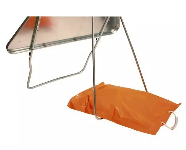 An orange PVC sandbag holds down a traffic sign to prevent it from falling down.