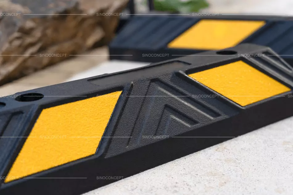 Black rubber parking stops with yellow reflective films are placed on the ground.