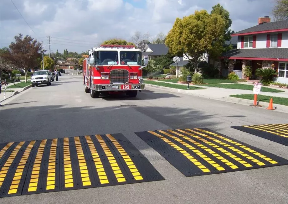 A fire truck is about to drive over some black and yellow speed cushions.