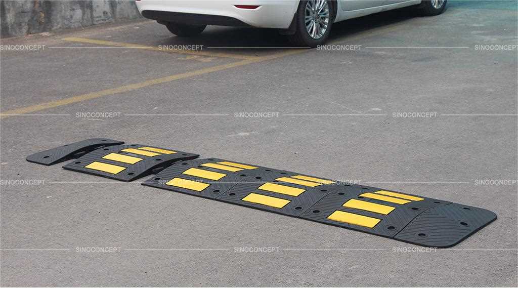 A black speed hump made of recycled rubber with yellow reflective films mounted on the road for traffic safety management.