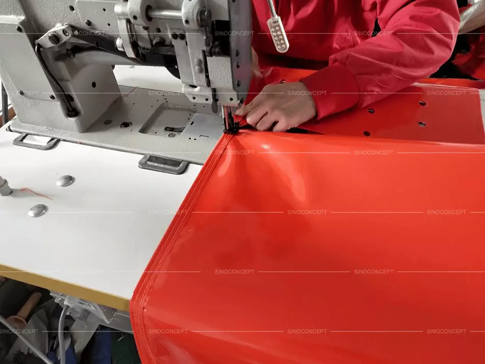 An orange sandbag is being made by a worker in the Sino Concept factory.