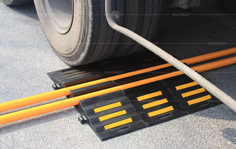 2-channel heavy-duty hose protector ramp made of black vulcanized rubber with glass bead reflective films.