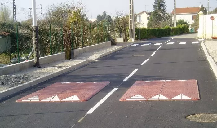 Two Europe red rubber road speed cushions are mounted on the road as speed traffic-management tools.
