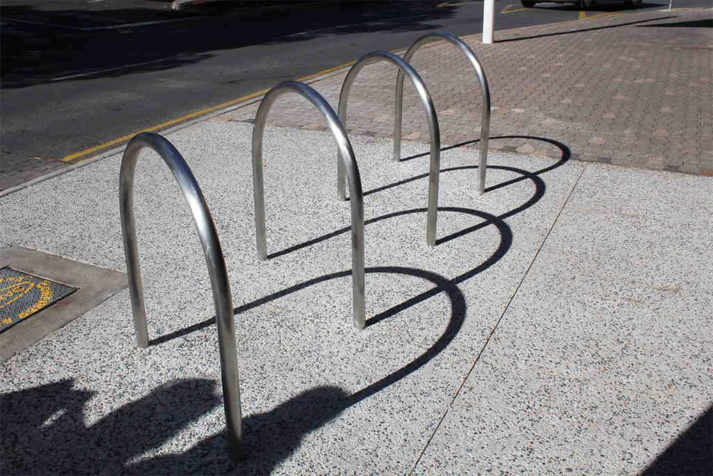 U cycle racks made of steel mounted on the ground, used for bicycle parking.
