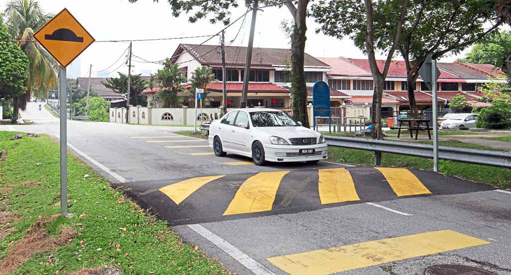 A black asphalt speed bump with yellow markings to reduce speed.