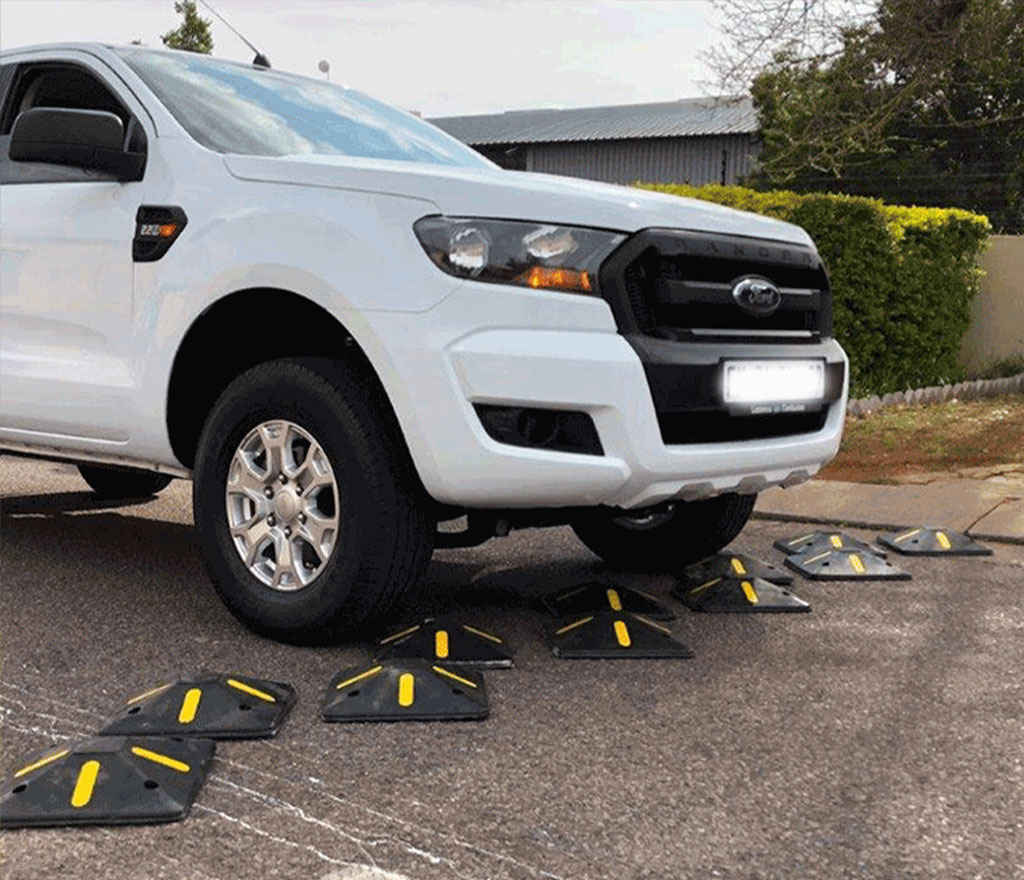 Black square speed bumps with yellow markings on the road for traffic management.